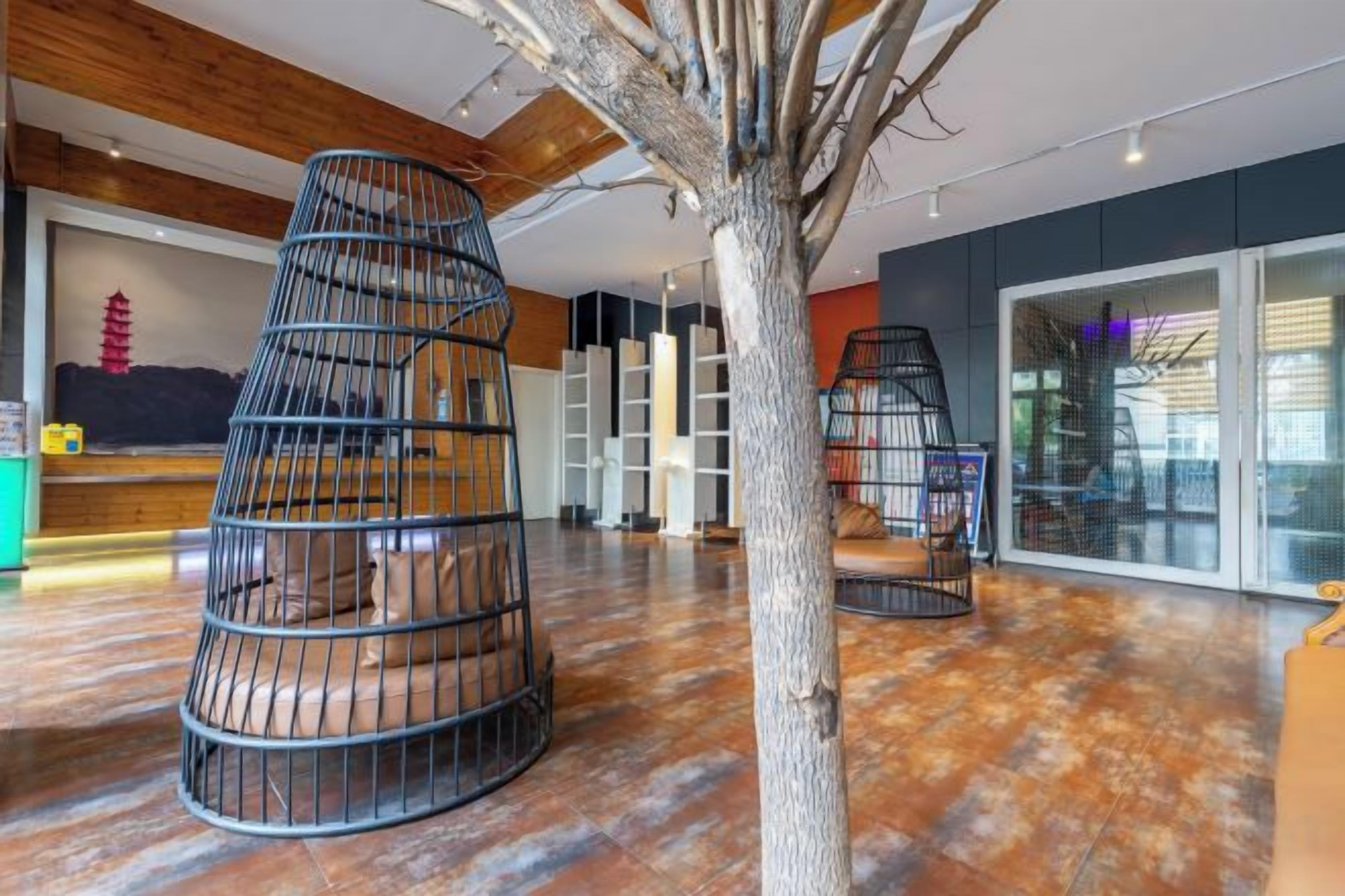Interior moderno com escadaria em espiral, uma árvore e uma área de recepção.