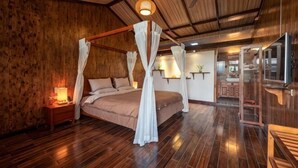 Una habitación con paneles de madera, una cama con dosel, un ventilador de techo y un televisor.
