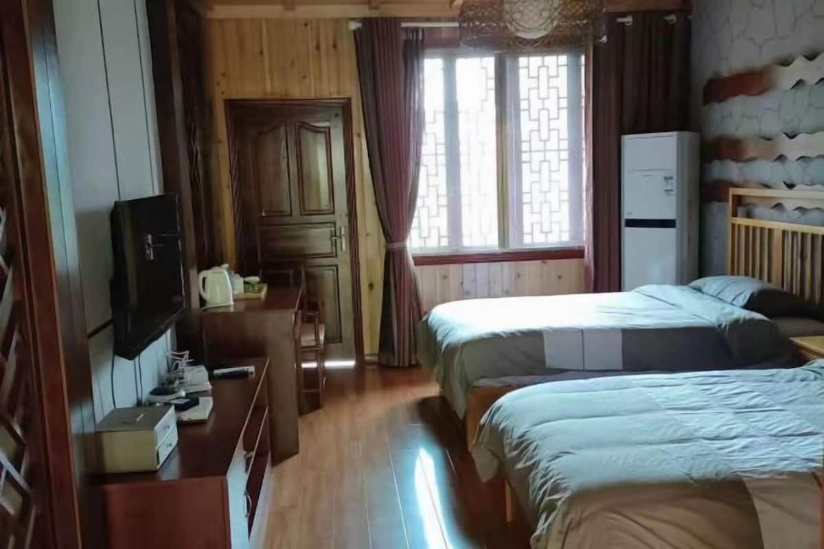 A room with two beds, a wooden wardrobe, a television, and a refrigerator.