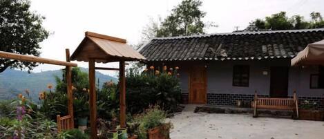 A traditional house with a tiled roof, a wooden porch, and potted plants.