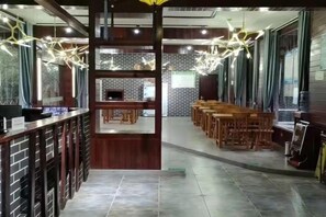 Ein Restaurantinneres mit Barbereich, Holztischen und hängenden Lampen.