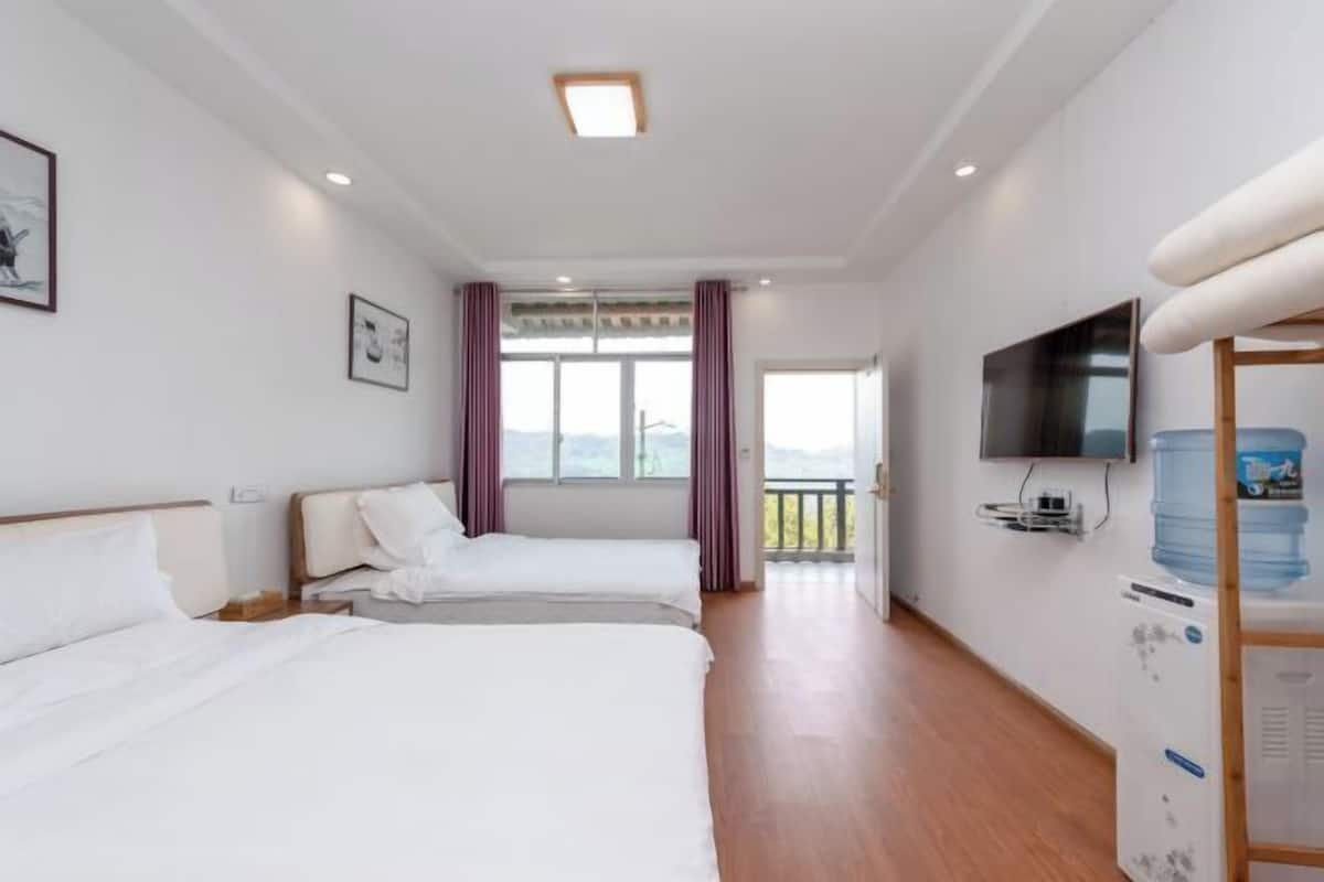 A hotel room with two beds, a television, a water dispenser, and a balcony with a view.