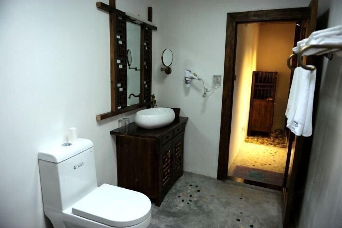 A bathroom with a toilet, sink, mirror, and towel rack.