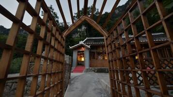 A traditional wooden gate leading to a building with a tiled roof and a stone pathway.