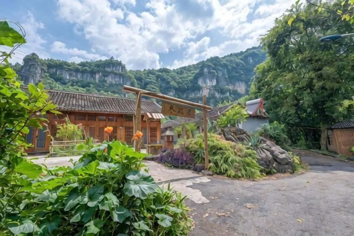 A traditional building with a wooden structure, a signboard, and a mountainous backdrop.