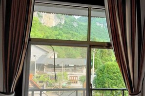 A window with curtains, offering a view of a traditional building and lush greenery. - Yuqingfang Hongdu Hostel (Yuqing)