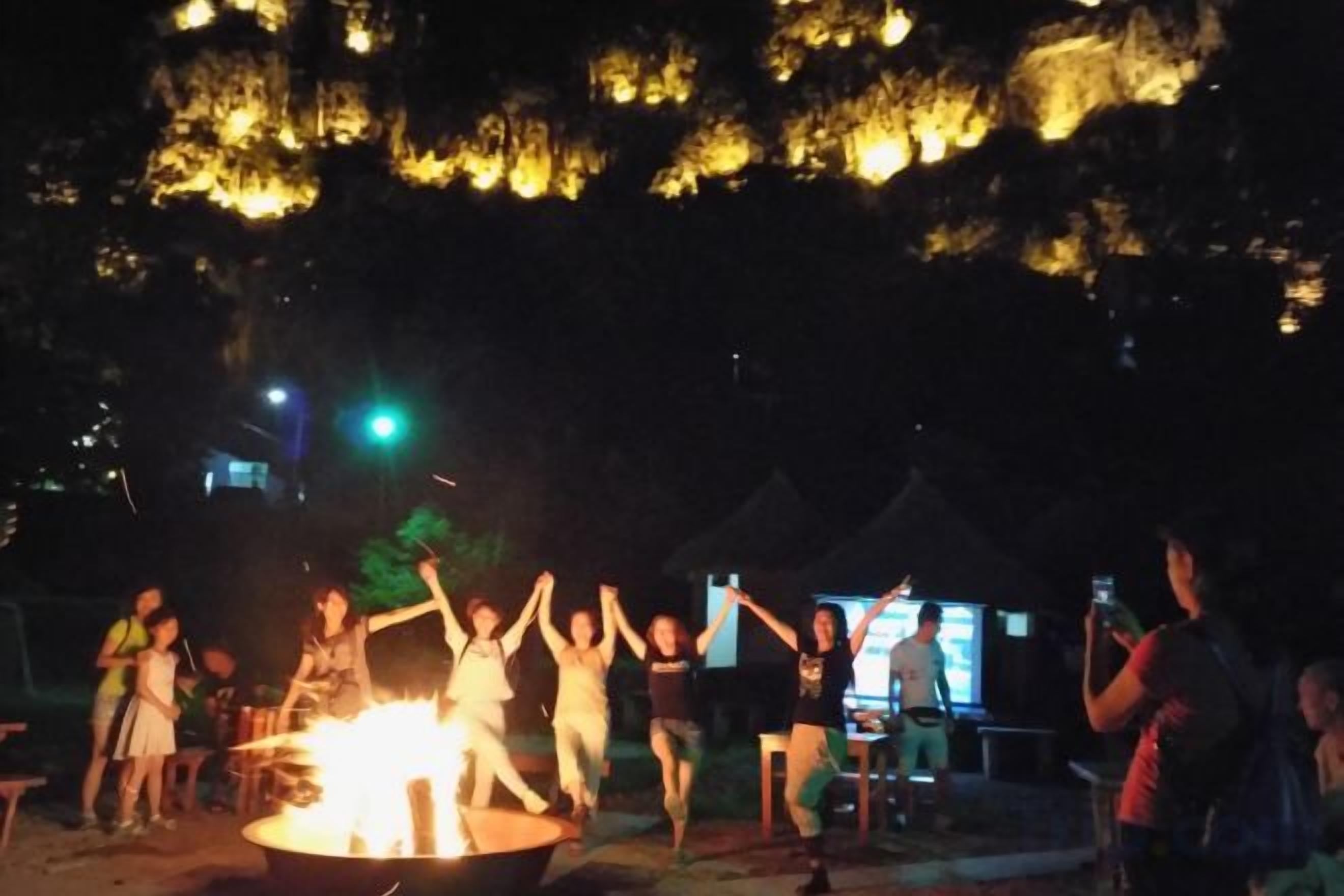 A group of people gathered around a campfire at night.