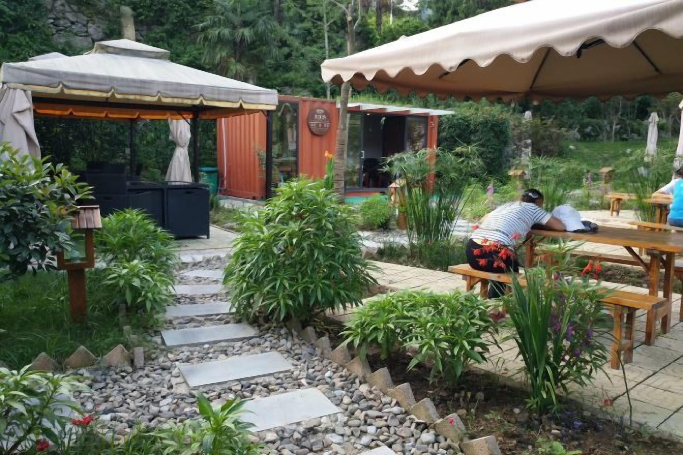 Un jardín con un sendero de piedra, bancos de madera y una zona de estar cubierta.