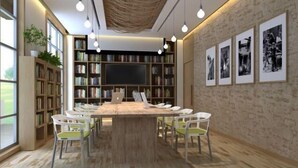 Una biblioteca moderna con una amplia mesa de madera, sillas blancas y estanterías llenas de libros.