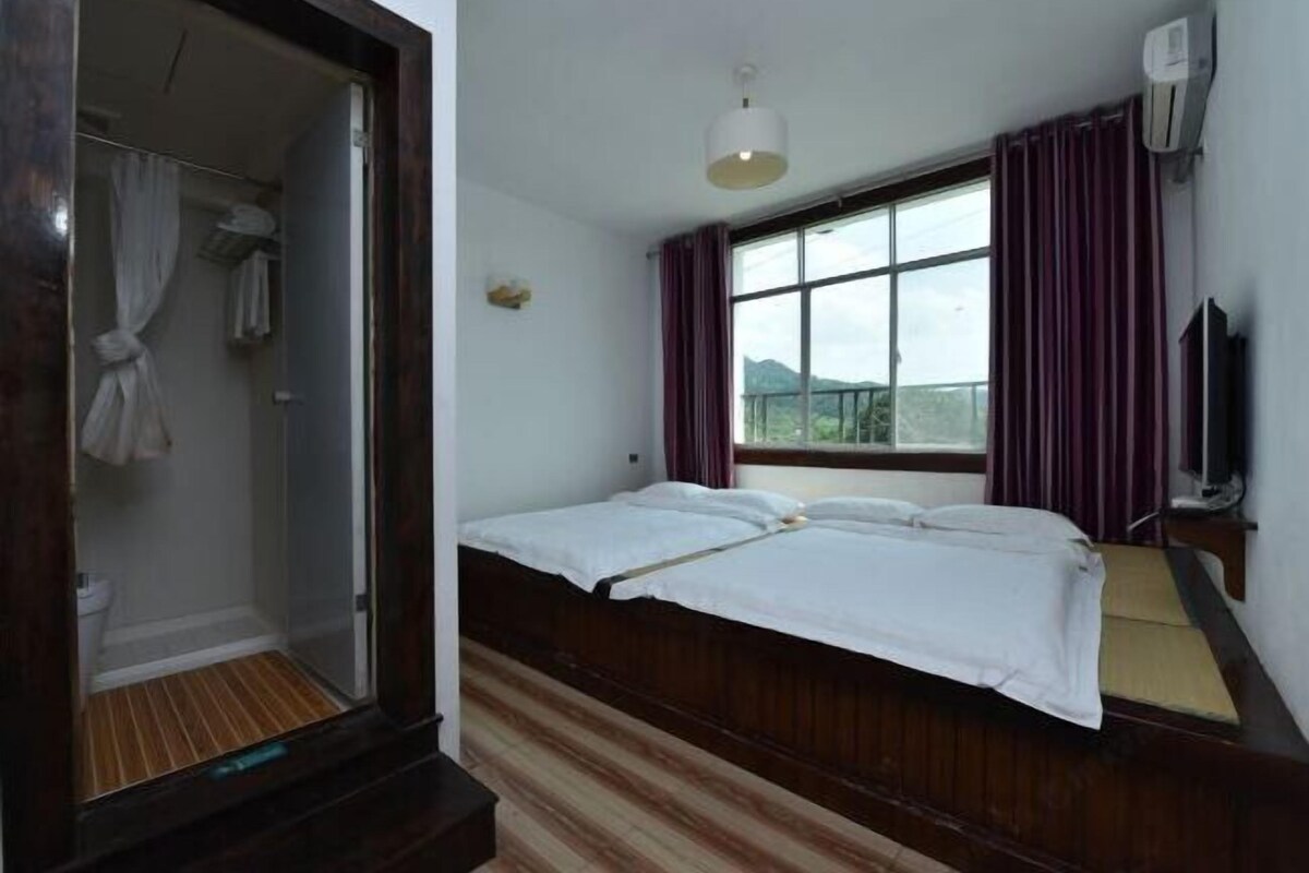 A room with a bed, a shower, a window with curtains, and a TV.