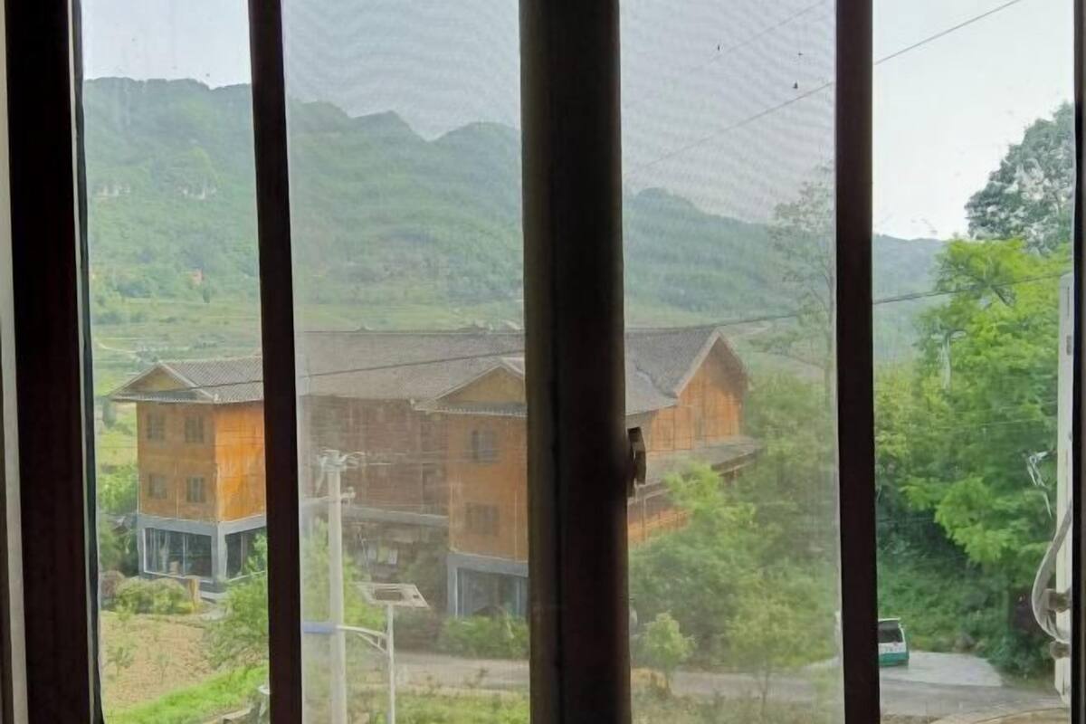 A view through a window with a view of a building and greenery.