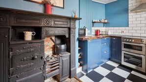 Une cuisine dotée d’un fourneau d’époque, d’appareils électroménagers modernes et de meubles de couleur bleue.