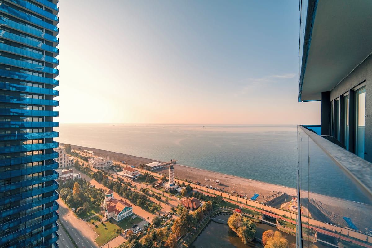 A high-rise building with a view of a coastal area, including a beach and a body of water.