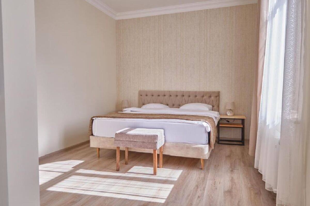 A neatly arranged bedroom with a large bed, bedside tables, and a small bench.