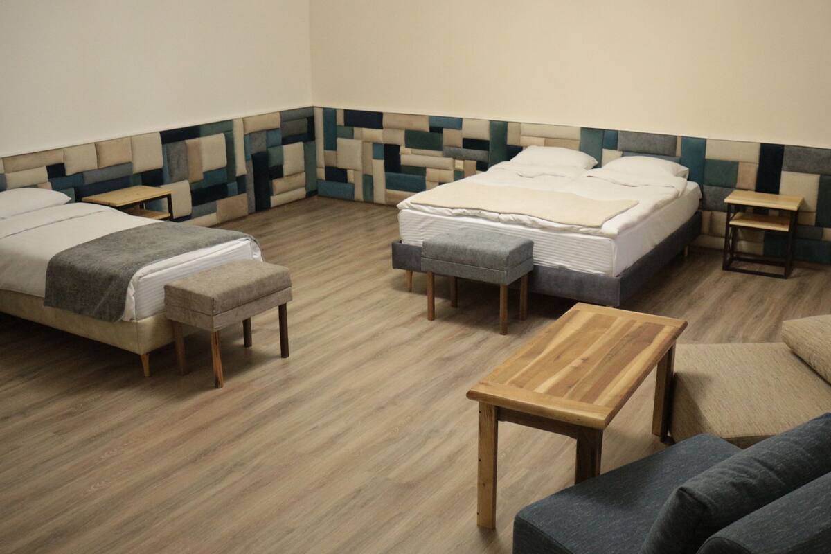 A hotel room with two beds, a wooden table, and a sofa.
