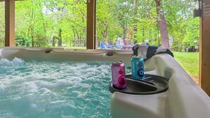 Ein Whirlpool mit Blick auf eine üppige, grüne Landschaft durch große Fenster.