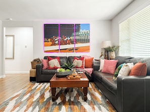 A living room with a black leather sofa, a coffee table, and a colorful rug.