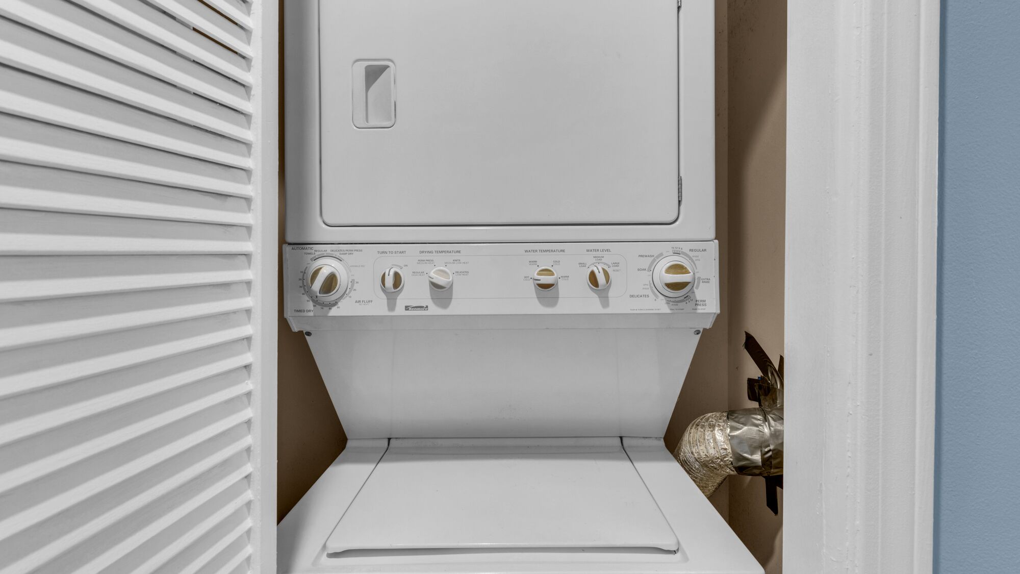 A front view of a front-loading washing machine with control knobs for temperature and settings.