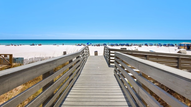 A wooden boardwalk leading to a beach with clear skies.