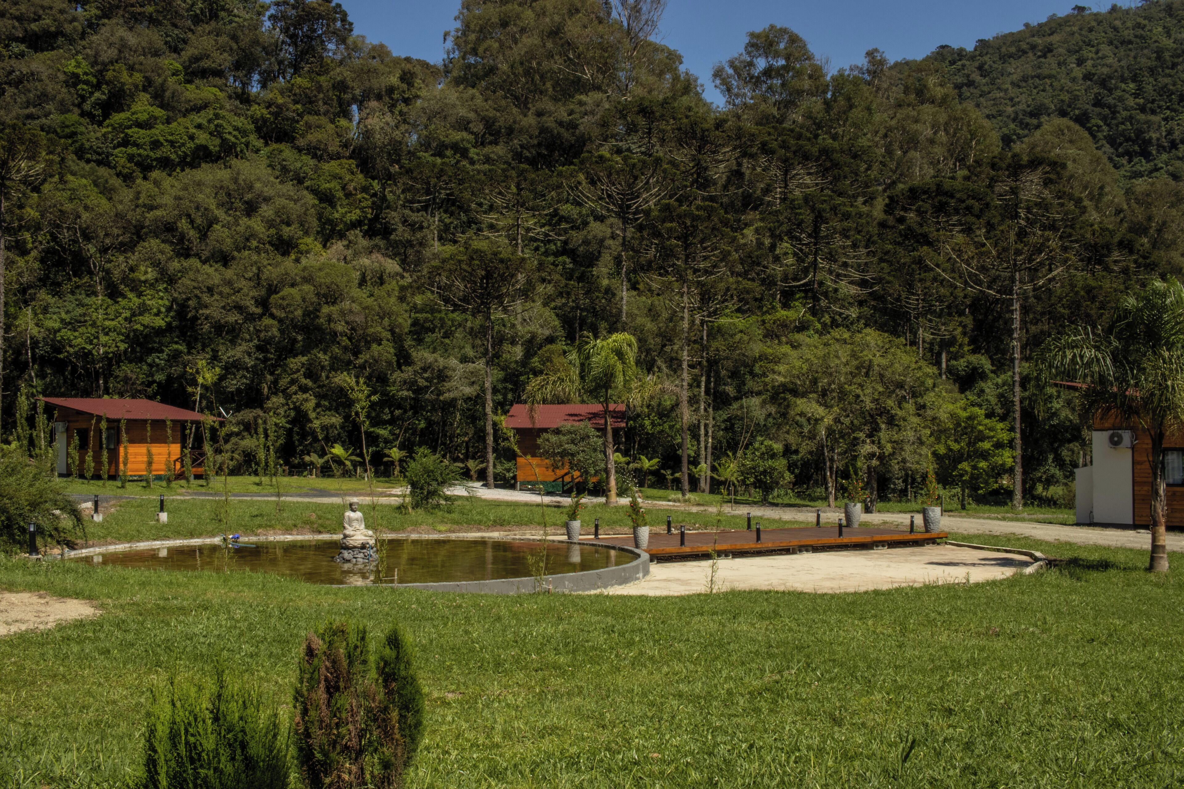 Un parque tranquilo con un estanque, un pequeño puente y un pabellón.