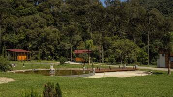 Un parque tranquilo con un estanque, un pequeño puente y un pabellón.