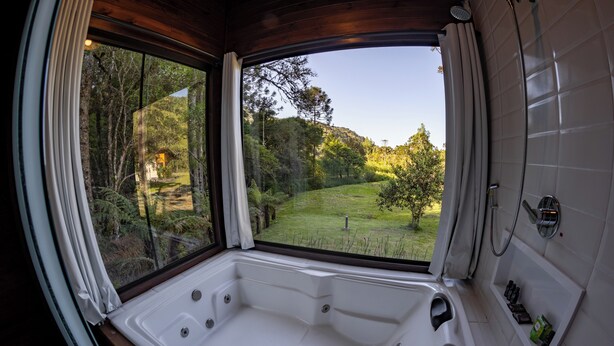 Un baño con un amplio ventanal que ofrece vistas a una zona boscosa.