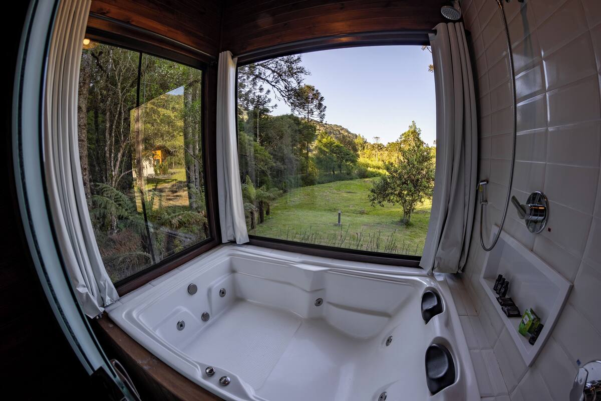 A bathroom with a large window offering a view of a forested area.