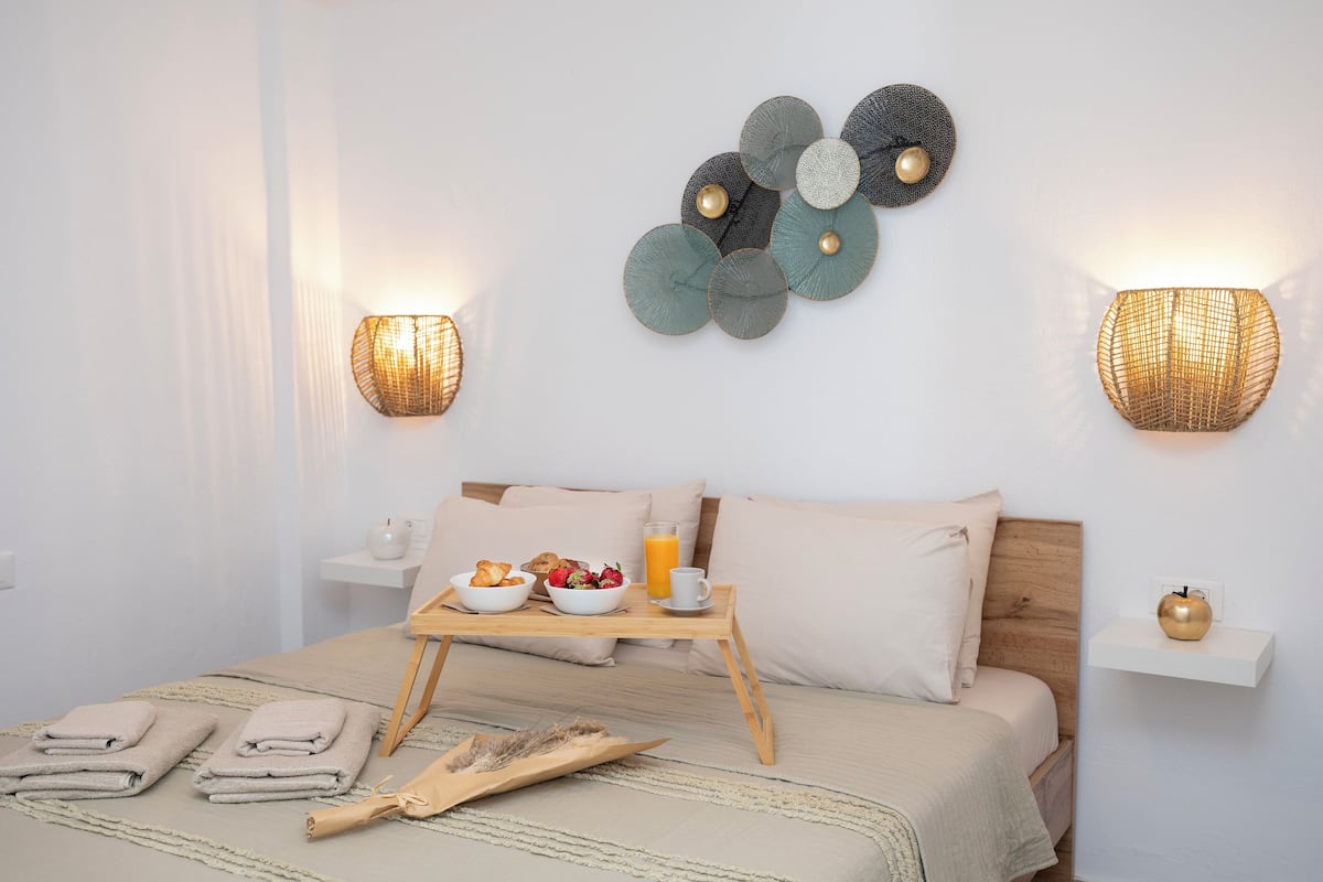A neatly made bed with a breakfast tray, towels, and a bedside table with a lamp.