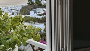 Vista desde una ventana con marco blanco, que da a una zona costera con edificios y vegetación.