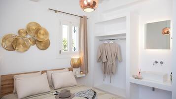 Un dormitorio con cama, mesita de noche, lámpara y vistas a un baño con lavabo y espejo.