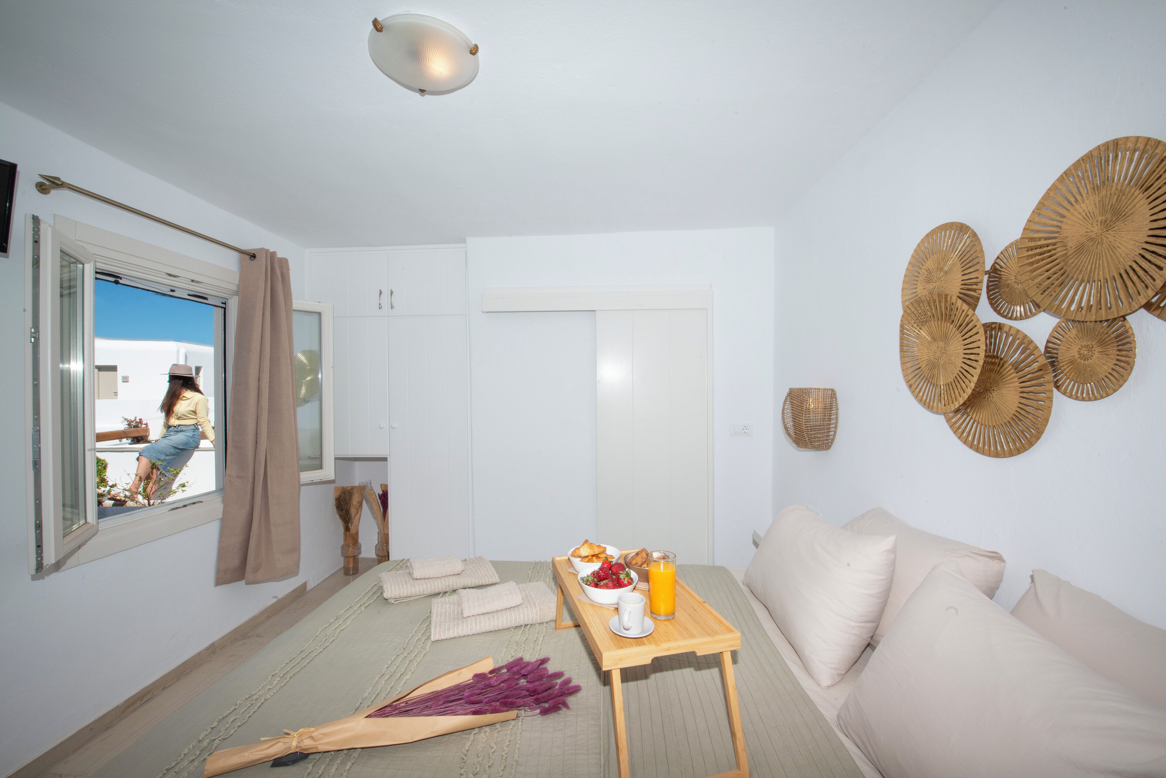 Une chambre d’hôtel moderne, équipée d’un lit, d’une table en bois où est servi le petit-déjeuner, d’un canapé et offrant une vue sur l’extérieur.