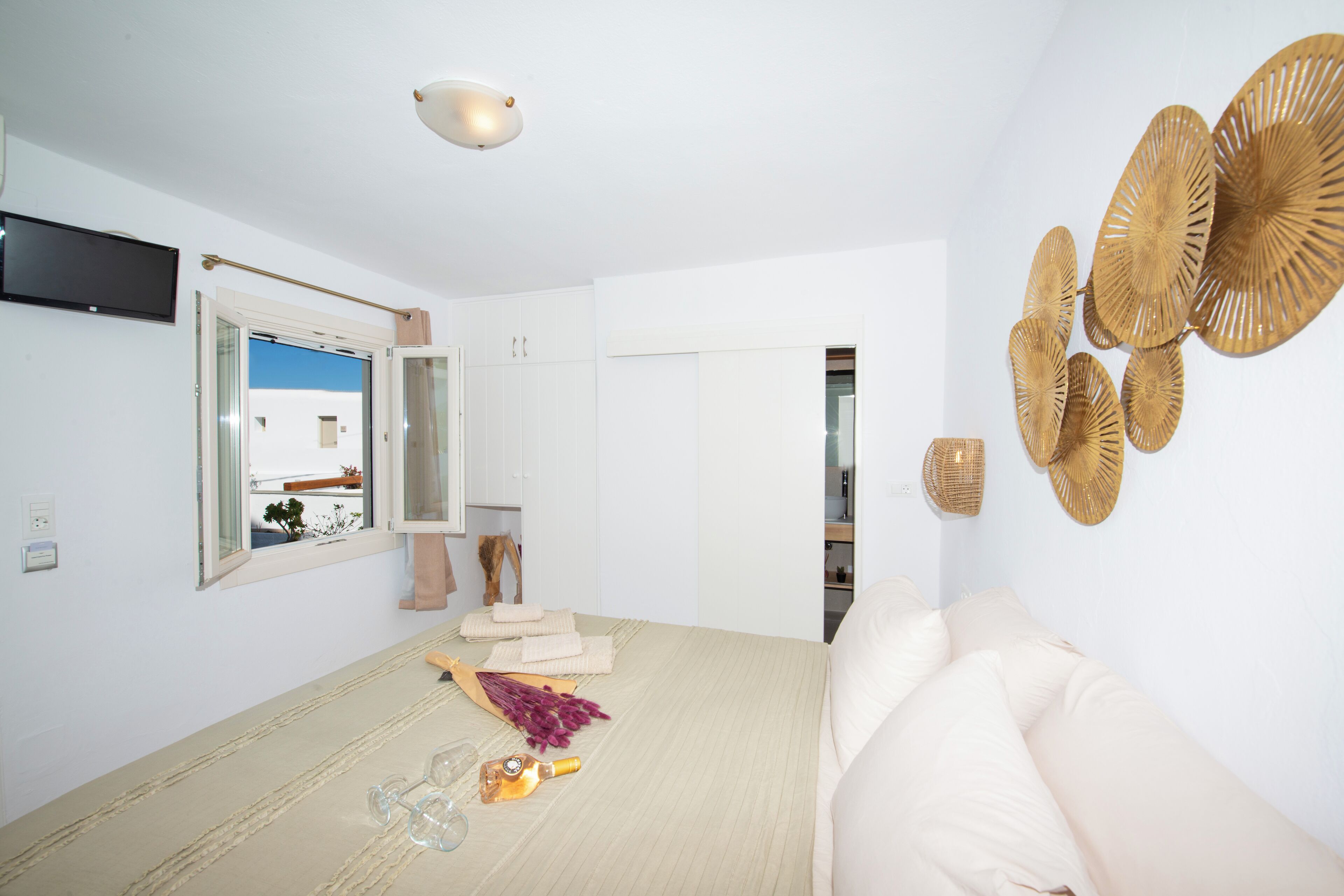 Ein modernes Schlafzimmer mit einem Bett, einem Fernseher und einem Fenster mit Blick auf ein Gebäude.