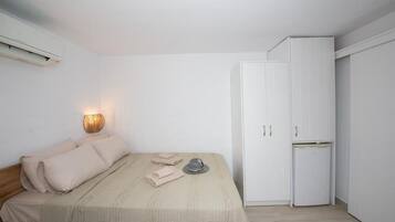 Un dormitorio con una cama, un armario y un aire acondicionado instalado en la pared.