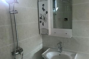 Un baño con ducha, lavamanos y espejo.