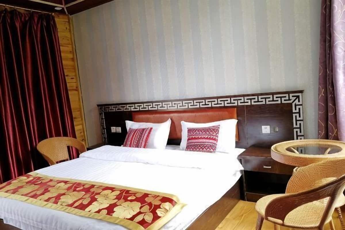 Una habitación de hotel con una cama, una mesa redonda de mimbre y una silla.