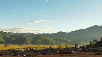 Un paysage rural avec des montagnes, un ciel dégagé et des bâtiments traditionnels.