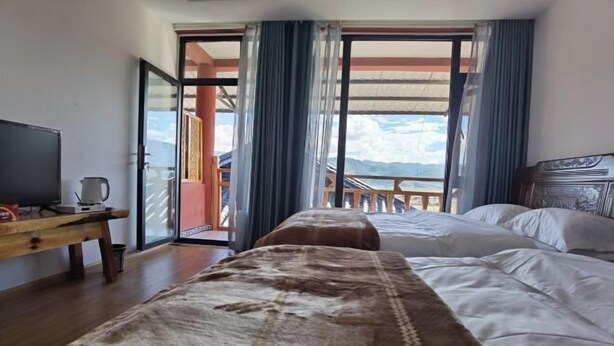 Una habitación de hotel con cama, televisión, una mesa de madera y balcón con vistas.
