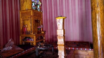 Een klassieke kamer met een houten kast, een hoge houten standaard en een gestreept bankje.