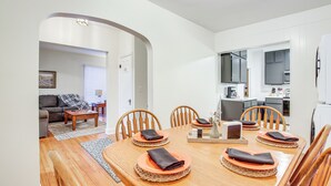A dining area with a wooden table set for four, surrounded by chairs. There is a kitchen visible in the background. - Barnes City House ~ 3 Mi to Hunting & Fishing! (Barnes City)