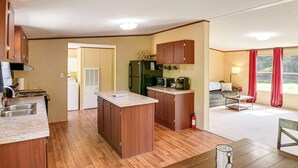 Een compacte keuken met houten kastjes, een centraal eiland, een koelkast, magnetron en een spoelbak.