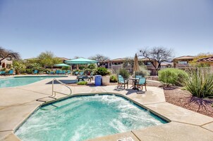 A swimming pool with lounge chairs and umbrellas, surrounded by houses.