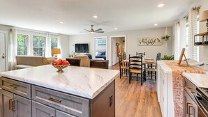 A modern kitchen with a marble countertop, wooden flooring, and a dining area with a table and chairs.