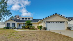 A single-story house with a garage, a front yard with a palm tree, and a clear blue sky. - Sunny Ocala Oasis w/ Grill: Near National Forest! (Ocala)