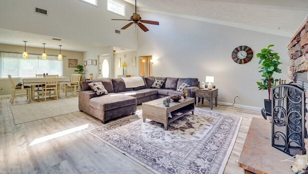 A spacious living room with a sectional sofa, a coffee table, and a patterned rug. There is a dining area with a table and chairs, and a kitchen in the background. - Sunny Ocala Oasis w/ Grill: Near National Forest! (Ocala)