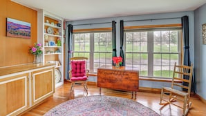 A room with a wooden cabinet, a pink chair, a wooden desk, and a large window with curtains. - Views of Canandaigua Lake: Middlesex Retreat! (Rushville)