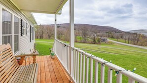 A wooden deck with a bench, white railing, and a view of a green field and hills. - Views of Canandaigua Lake: Middlesex Retreat! (Rushville)