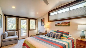 Un dormitorio con una cama grande, una silla, una mesita de noche y una ventana con persianas.