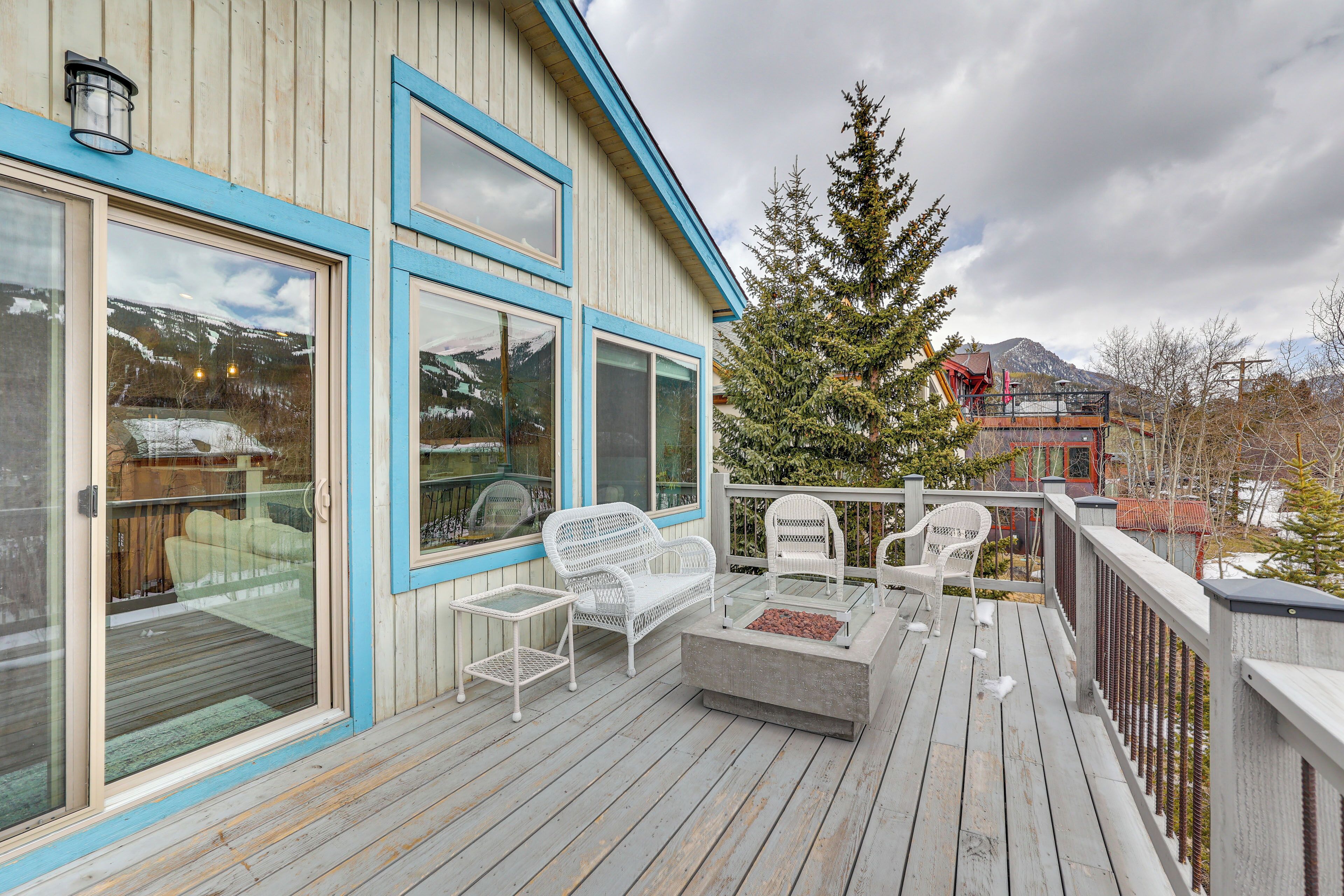 A wooden deck with white outdoor furniture, including a sofa and chairs, and a glass-top table.