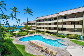 A hotel with a pool area, multiple balconies, and a view of the ocean. - White Sands Village#206: Beachfront, Ocean Views, Elevator, No Stairs! (Kailua Kona)
