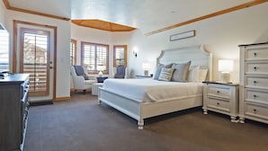 Een slaapkamer met een groot bed, een dressoir, een stoel en een bureau.